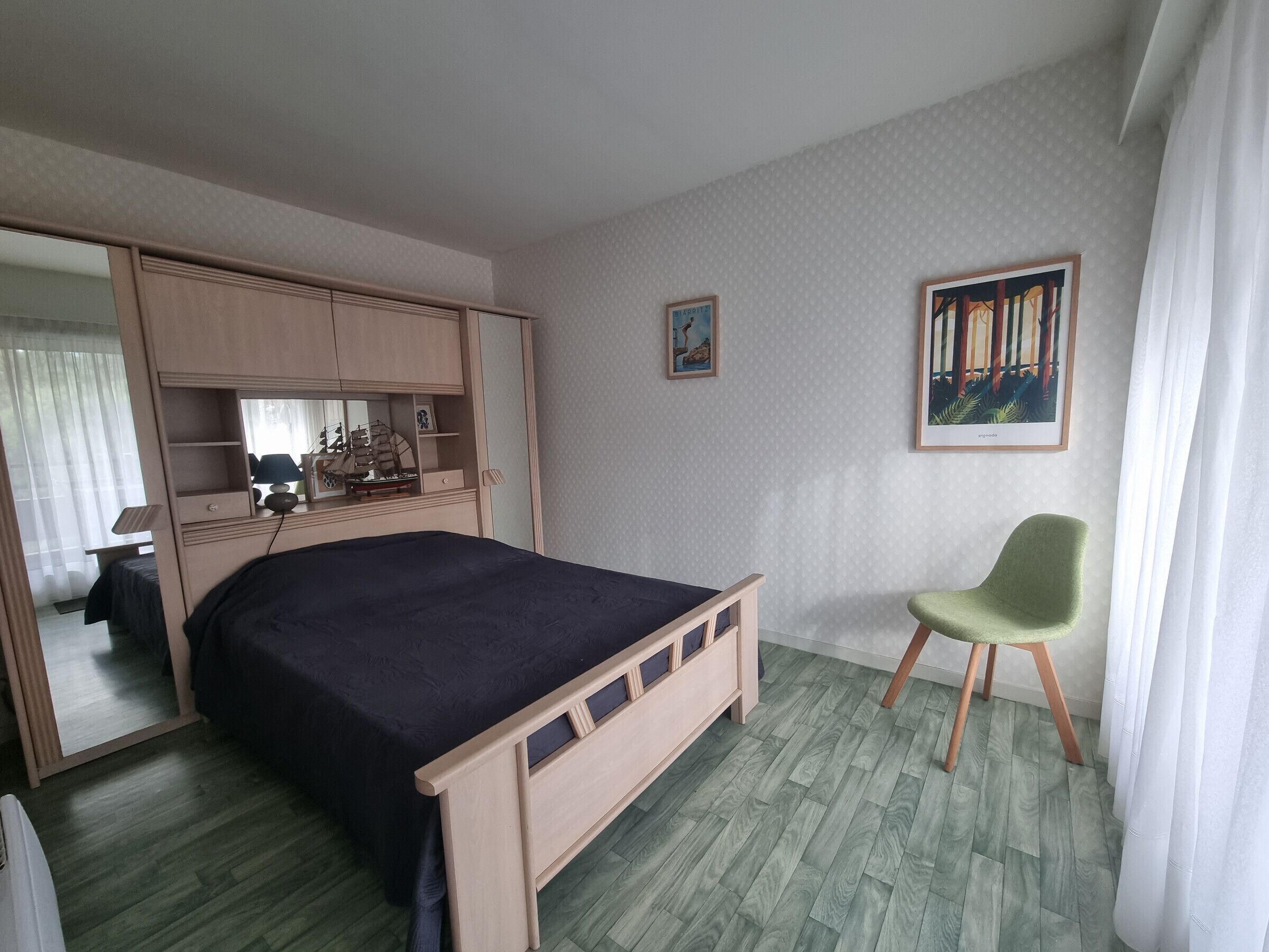 Ein Schlafzimmer mit einem Bett, einem Sessel, einem Schreibtisch und einem Kleiderschrank.