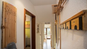 A hallway with a wooden door labeled "Schloss," a coat rack, and a hanging coat. - Kleine Wohnung Nahe Winterberg mit Terrasse (Winterberg)
