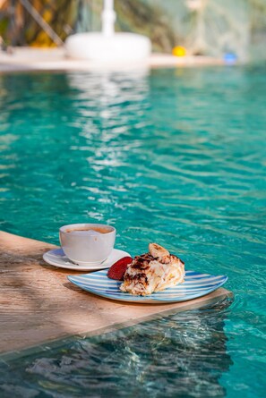 A dining table by a pool with a cup of coffee and a plate of food. - Anzede Konaklama Çeşme (Çesme)