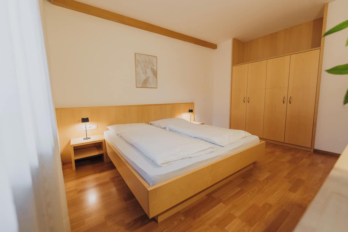 Una camera da letto con un letto di legno, un comodino con una lampada e armadi di legno.