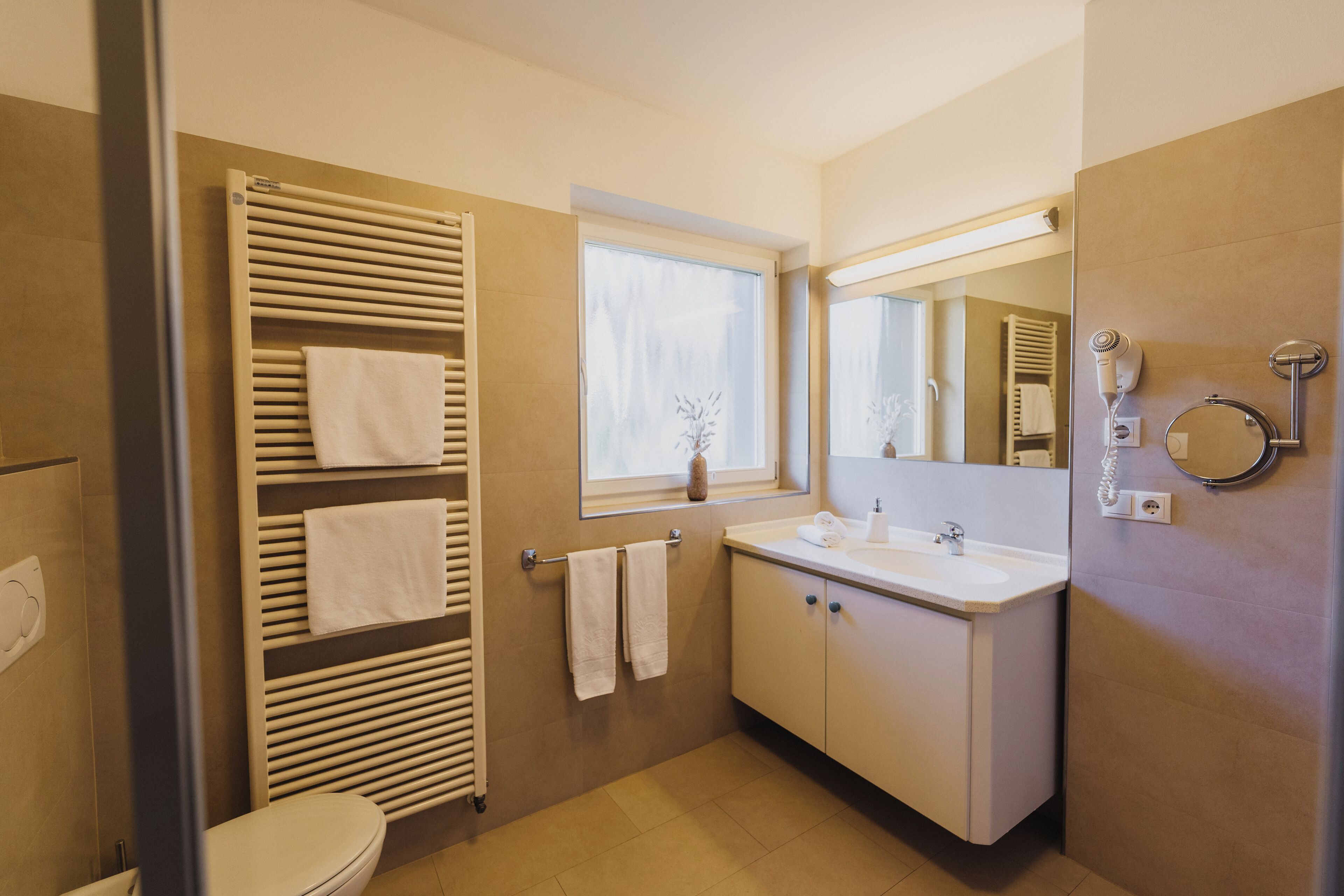 A modern bathroom with a built-in towel rack, a window, a sink, and a mirror.