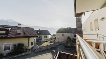 A residential street with houses, a stone wall, and a mountain in the background.