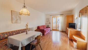 Ein geräumiger Wohnbereich mit Esstisch, Sofa und Fernseher-Schrank.
