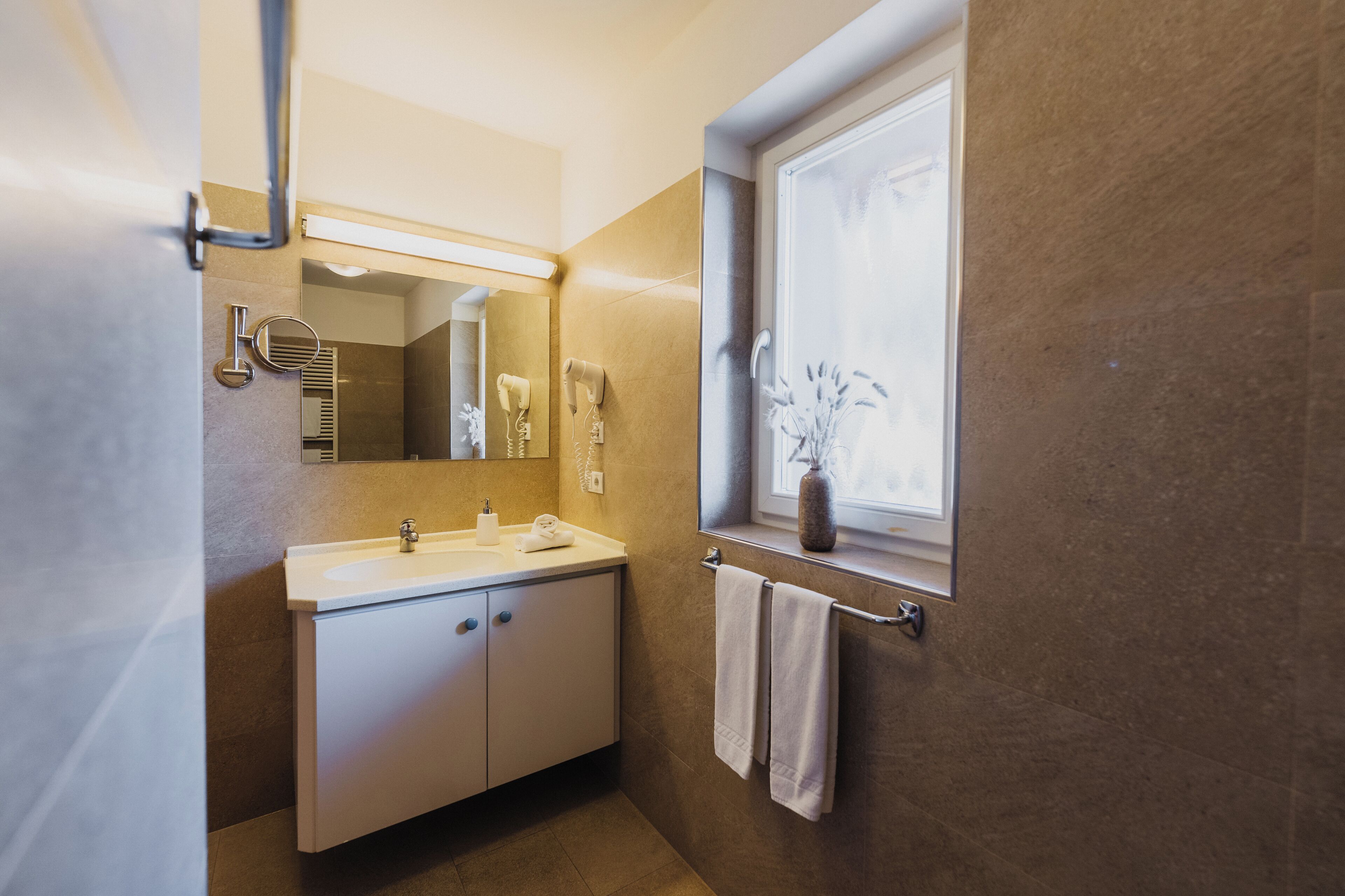 A modern bathroom with a white sink, mirror, and towel rack.