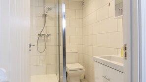 Ett modernt badrum med en dusch som är avskärmad med glasväggar, en toalett och ett handfat.