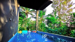 Une piscine à l’eau d’un bleu cristallin, entourée d’une végétation luxuriante et de palmiers.