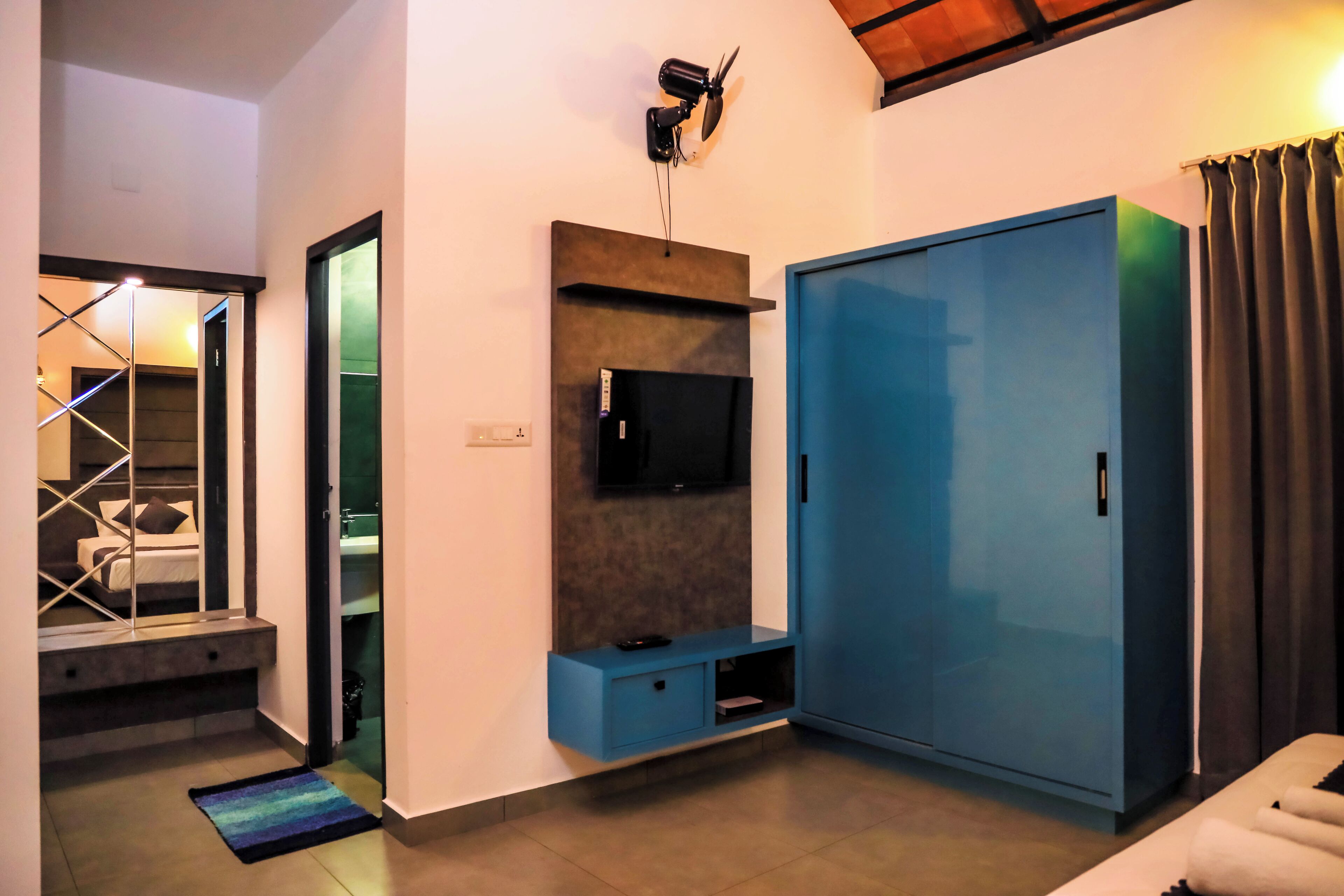 Une chambre moderne dotée d’une grande armoire, d’un téléviseur à écran plat fixé au mur et d’un petit coin salon agrémenté d’un tapis.