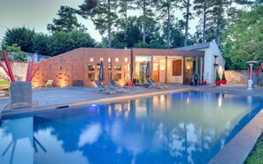 A modern pool area with a wooden structure, lounge chairs, and a clear pool.