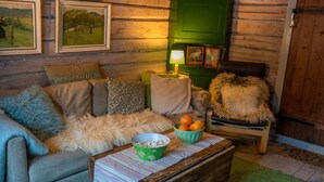 A cozy cabin interior with a sofa, armchair, and a coffee table with a bowl and oranges. - Cozy Cabin Retreat in Scenic Valley, E6 South of Trondheim (Midtre Gauldal)