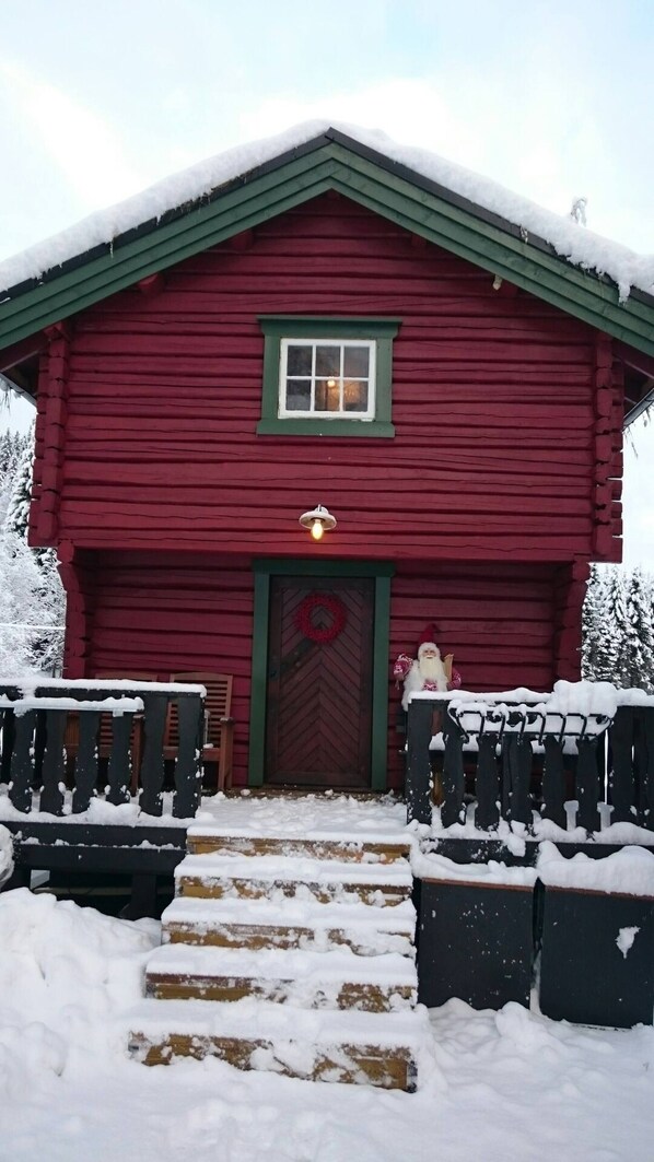 A red wooden building with a green roof, a front door with a wreath, and steps leading up to it. - Cozy Cabin Retreat in Scenic Valley, E6 South of Trondheim (Midtre Gauldal)