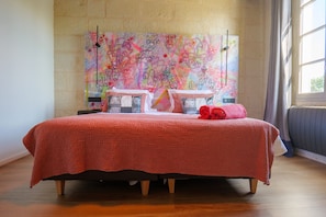 Ein Bett mit roter Decke, Kissen und gerolltem Handtuch.
