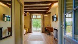Un corridoio con pavimento in legno, una sala da pranzo con sedie e tavolo, un angolo cottura con lavastoviglie e un'ampia finestra vista verde.