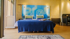 Una camera da letto con un letto grande, una testiera azzurra con motivo decorativo e vista sull'esterno.