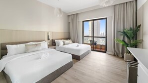 Quarto de hotel com duas camas, varanda e vista, além de um vaso com planta.