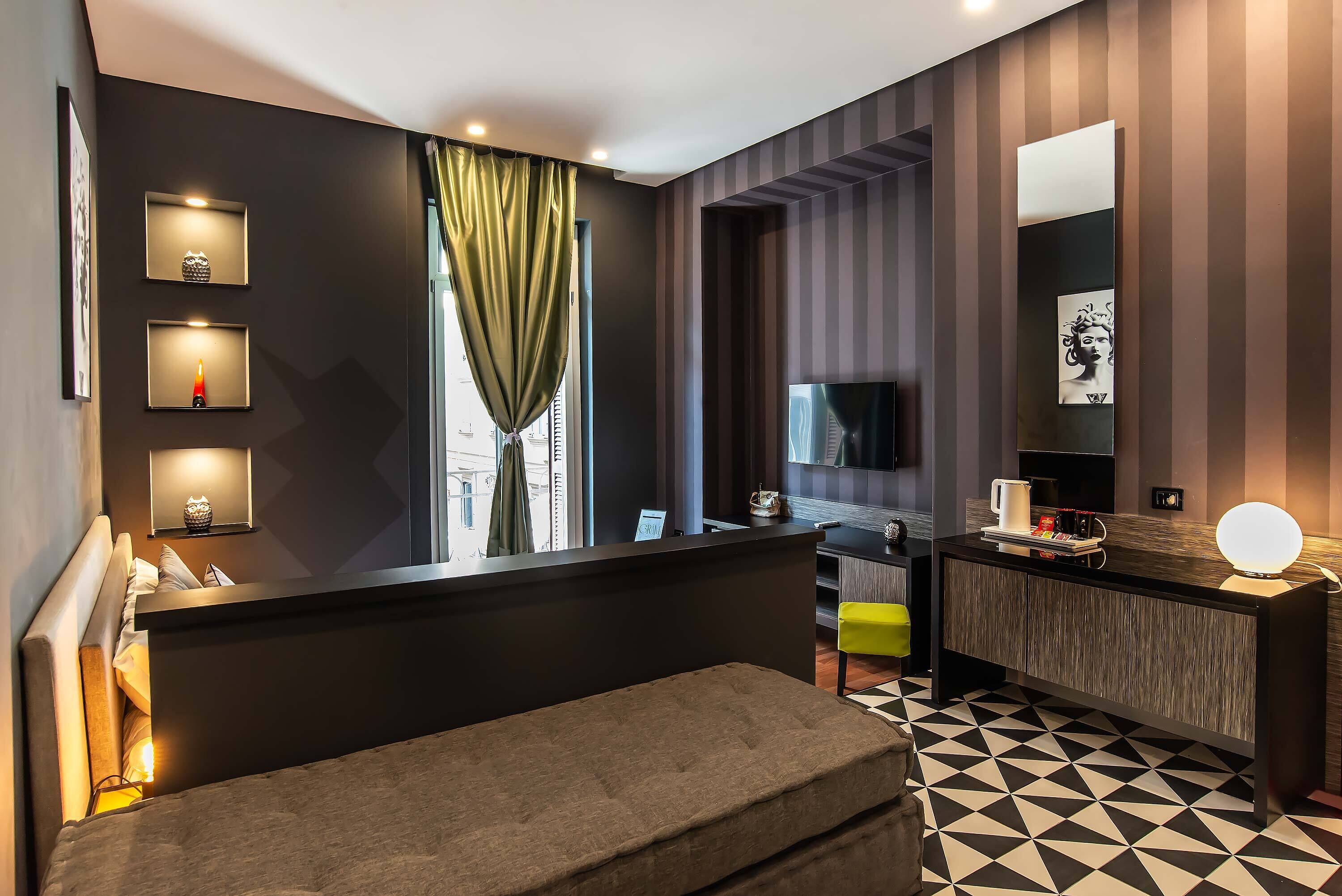 A modern hotel room with a bed, a desk, a TV, and a large window with curtains.