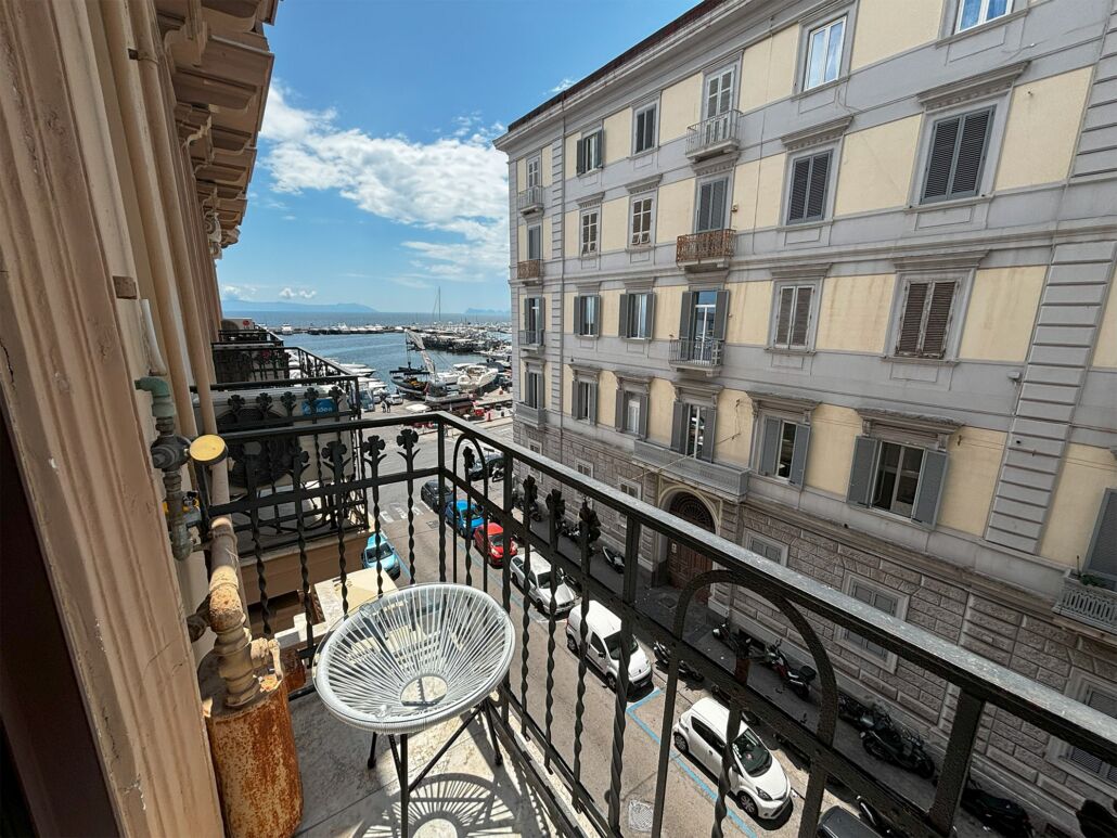 Ein Balkon mit Blick auf einen Jachthafen und ein Gebäude mit mehreren Fenstern und Balkonen.