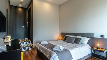 Quarto de hotel moderno com uma cama grande, uma escrivaninha e uma televisão.