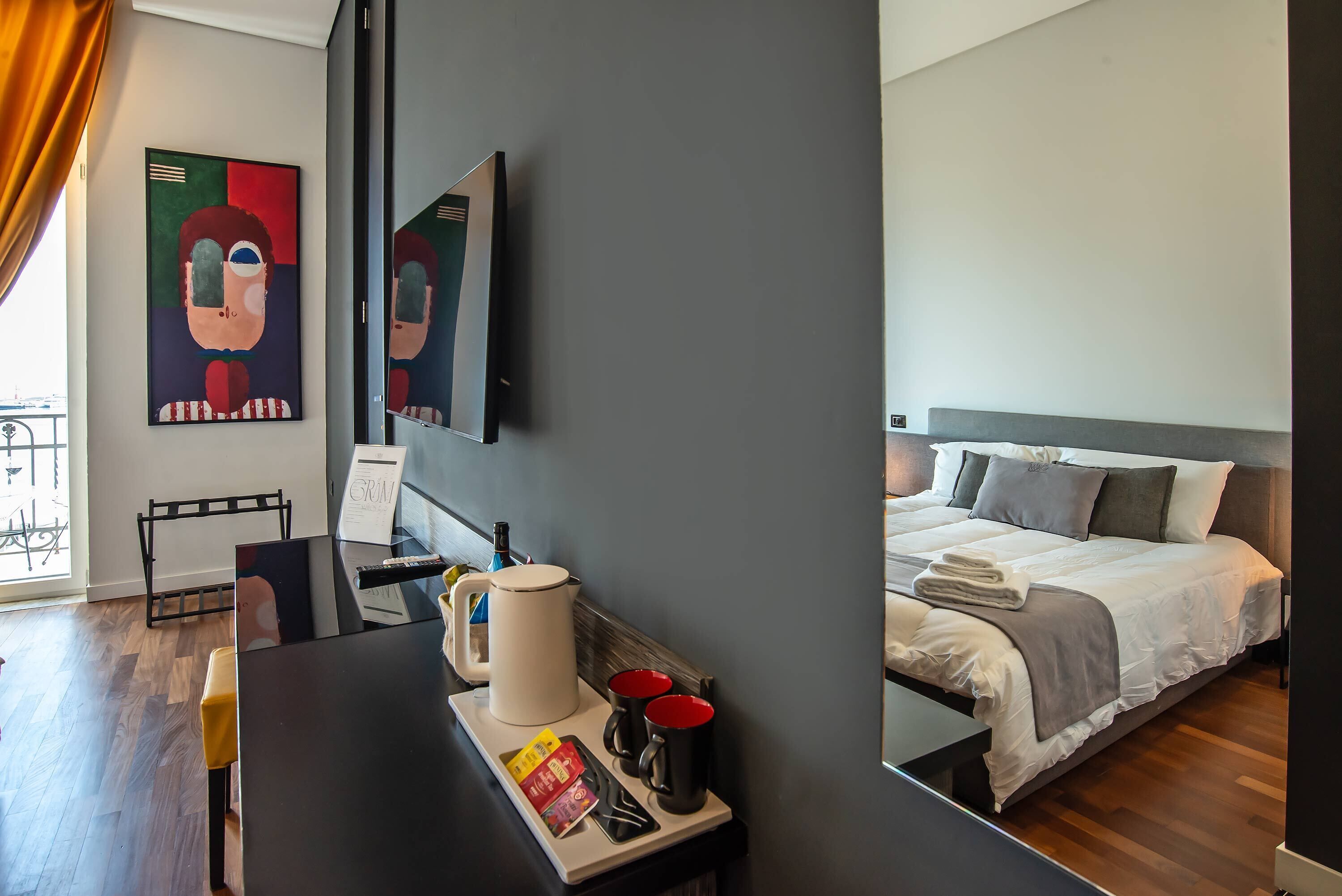 A modern hotel room with a bed, bedside table, and a large mirror.