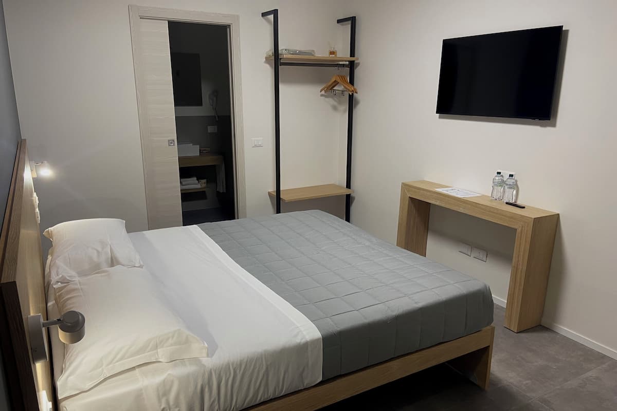 Une chambre d’hôtel moderne équipée d’un lit, d’un bureau, d’une télévision et d’une armoire.