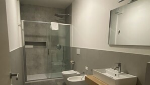 A modern bathroom with a glass shower enclosure, a toilet, and a sink with a mirror above. - Dormi-RE (Reggio nell'Emilia)