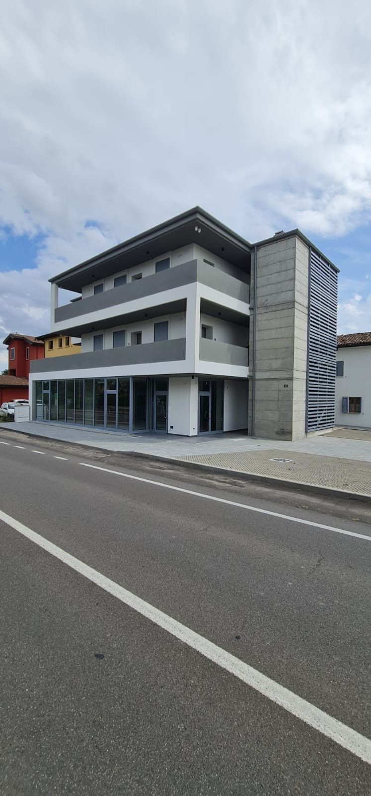 En moderne bygning med flere etager, fladt tag, store vinduer og en betonfacade.