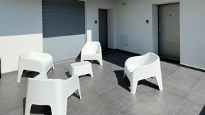 A modern outdoor seating area with white plastic chairs and a tiled floor. - Dormi-RE (Reggio nell'Emilia)