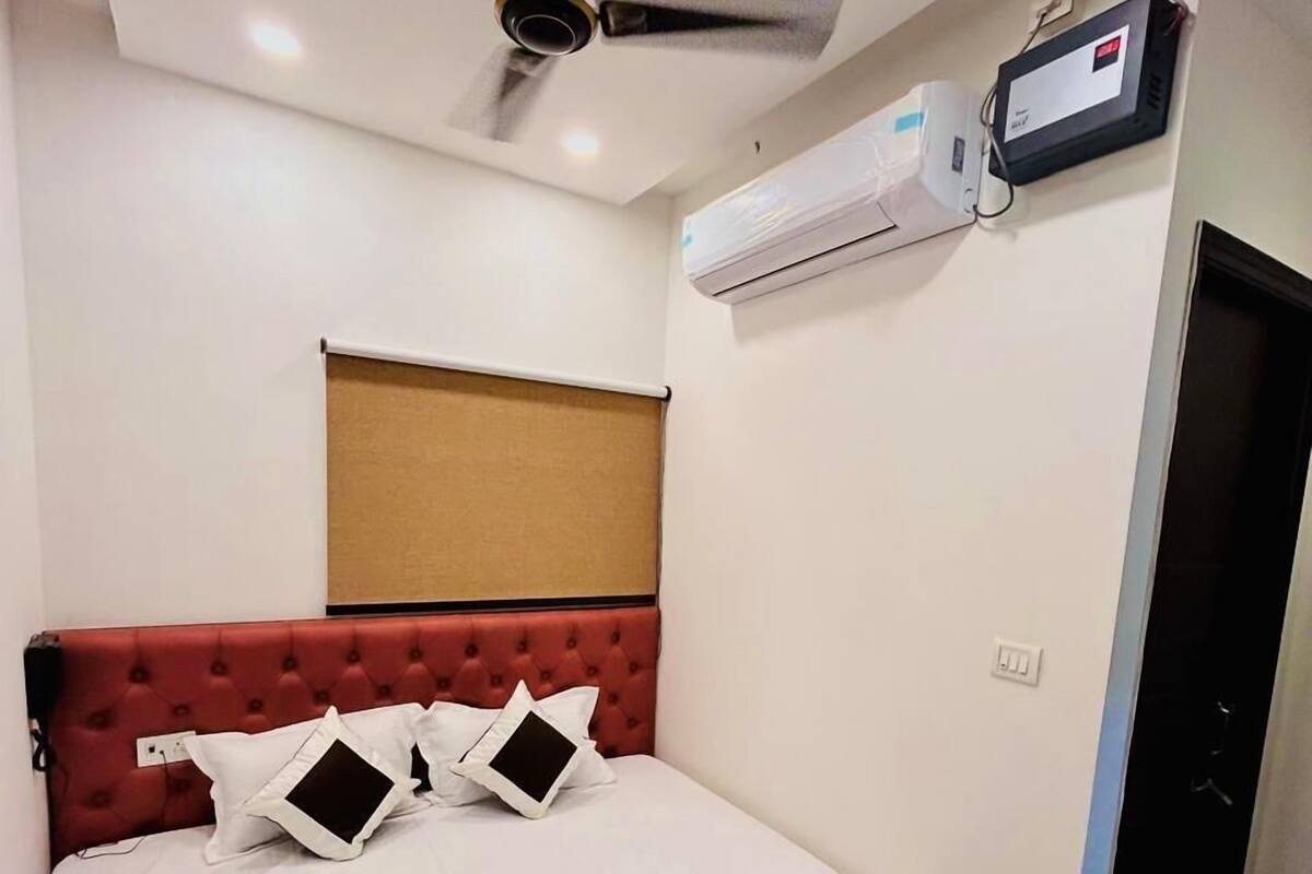 Un dormitorio con cabecera tapizada de rojo, edredón blanco y ventilador de techo.