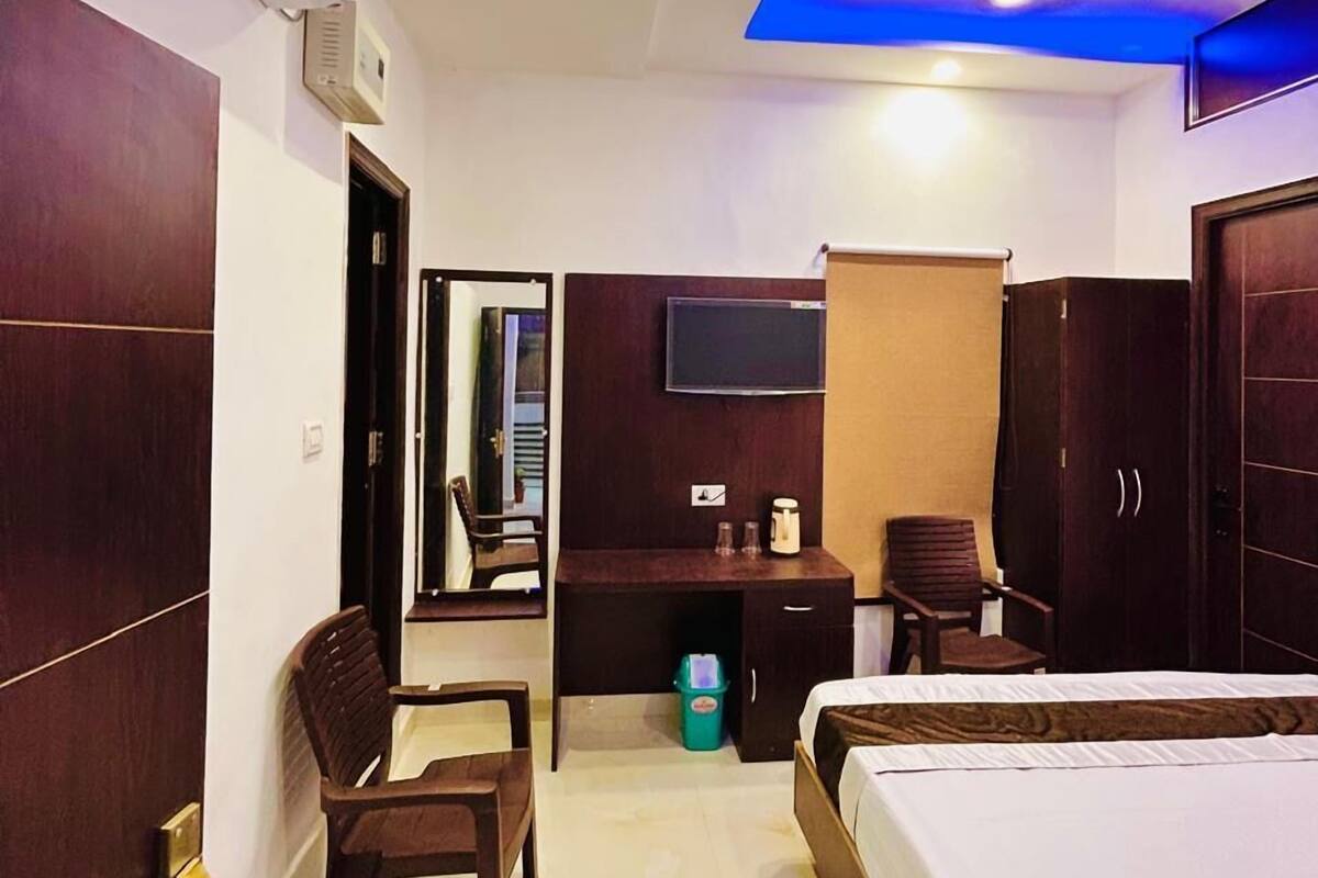 Una habitación de hotel con cama, escritorio, silla, televisor y ventilador de techo.