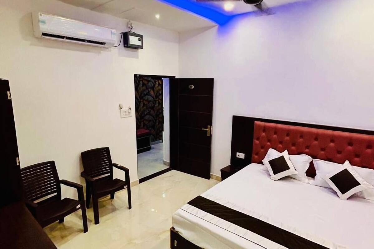 Un dormitorio con una cama, ventilador de techo, unidad de aire acondicionado y una puerta que da a otra habitación.