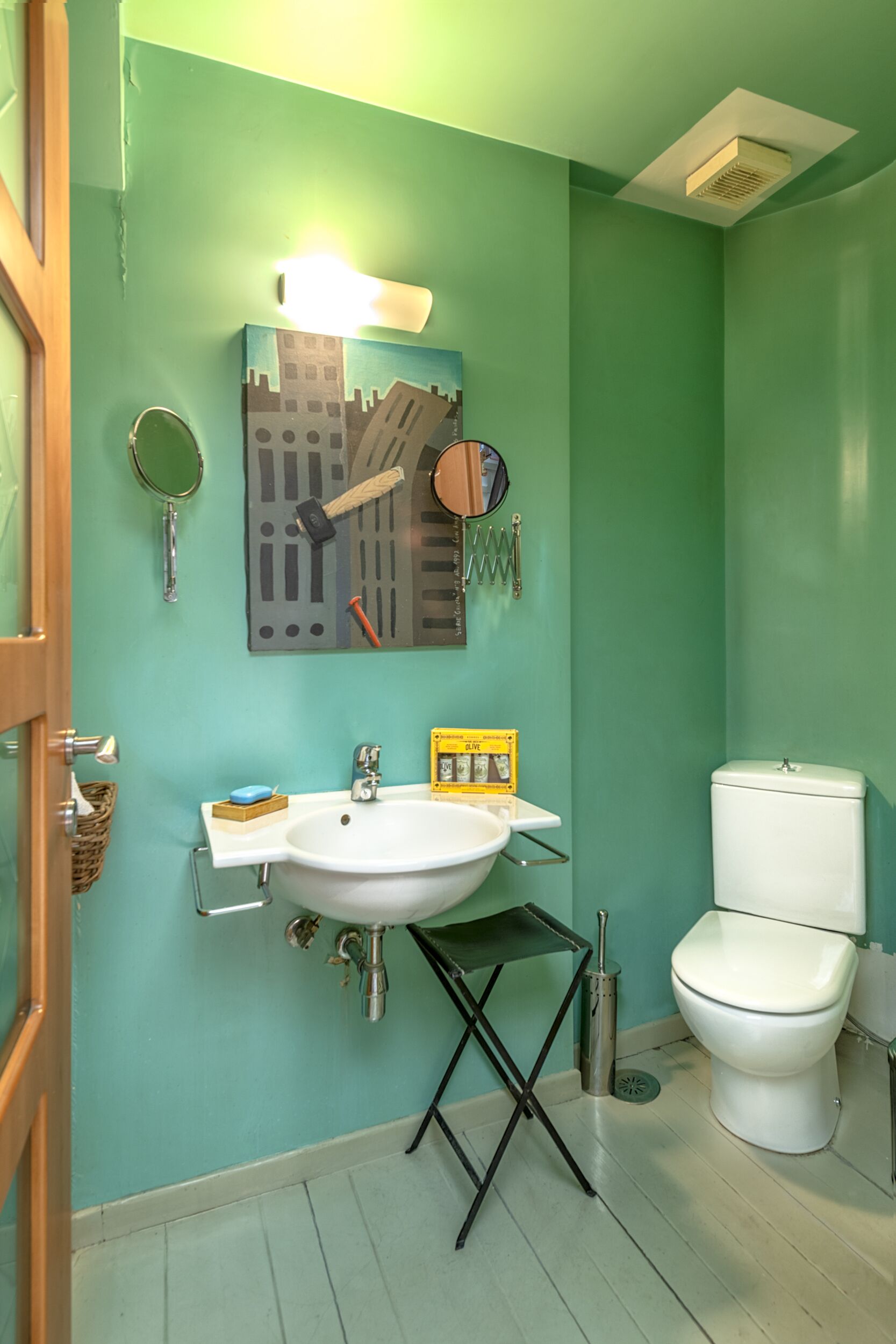 A bathroom with a white sink, a toilet, and a green wall.