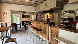 Eine Bar mit Barhocker, Theke und einer Kaffeemaschine.