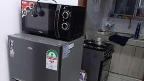 A compact kitchen with a refrigerator, a stove, and a microwave. - Lux Suites Rosavosa Apartments Bamburi (Mombasa)