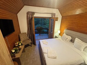 A bedroom with a bed, a chair, a TV, and a view of the outdoors. - Luxurious 5-bedroom villa with sauna,fireplace,grill place in beautiful Sinaia (Sinaia)