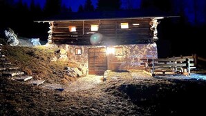 A rustic cabin with a wooden exterior, a central door, and multiple windows.