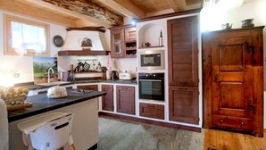A rustic kitchen with wooden beams, a large island, and built-in appliances.