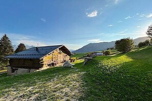 A rustic wooden cabin with a sloped roof, surrounded by a grassy landscape and distant mountains. - Maso 1445 - Breathtaking Views,Equipped Kitchen, Quiet,Starlink Int, Last min 5% (Primiero San Martino Castrozza)