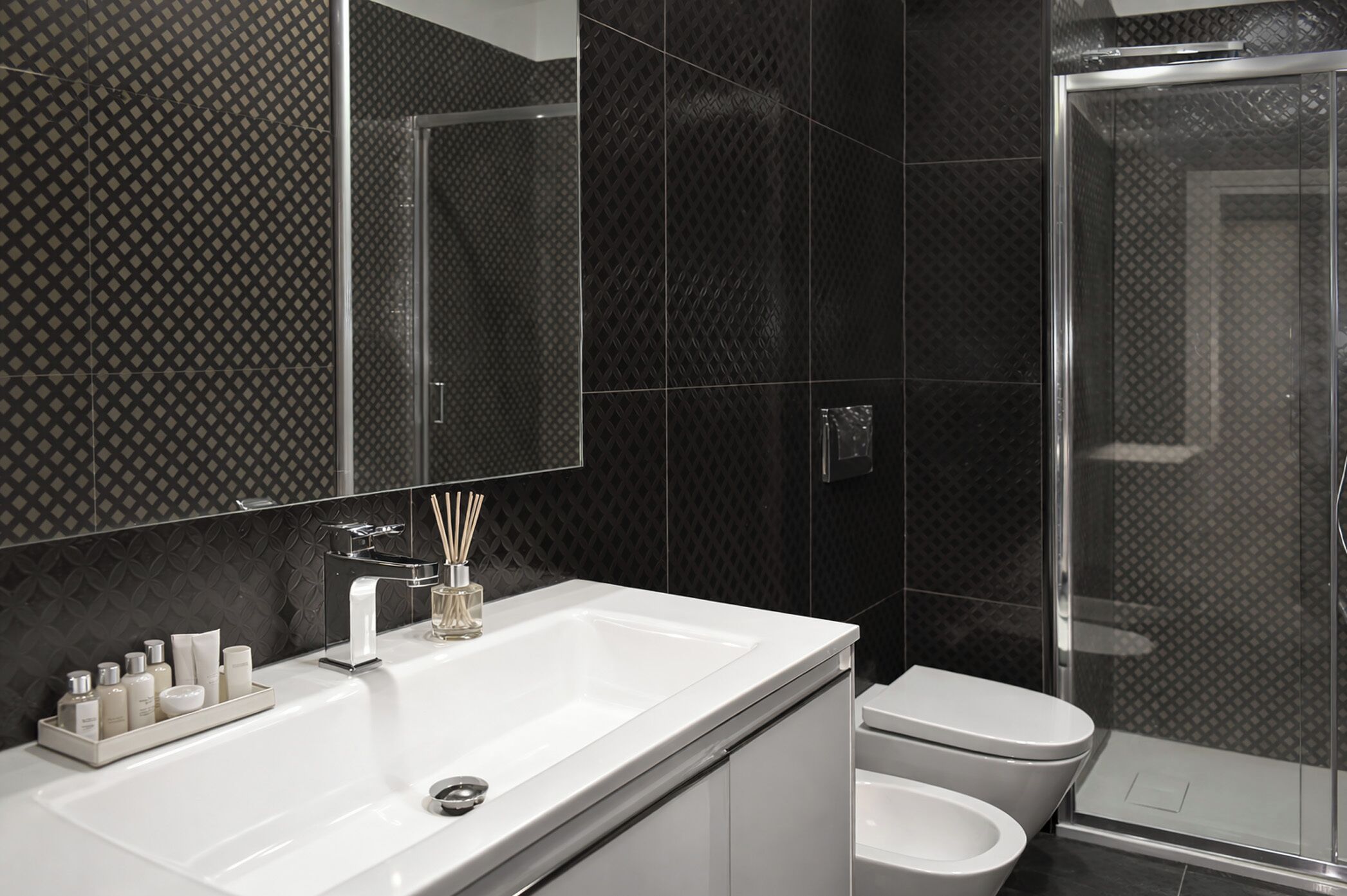 Un baño moderno con lavamanos, espejo y retrete blancos.