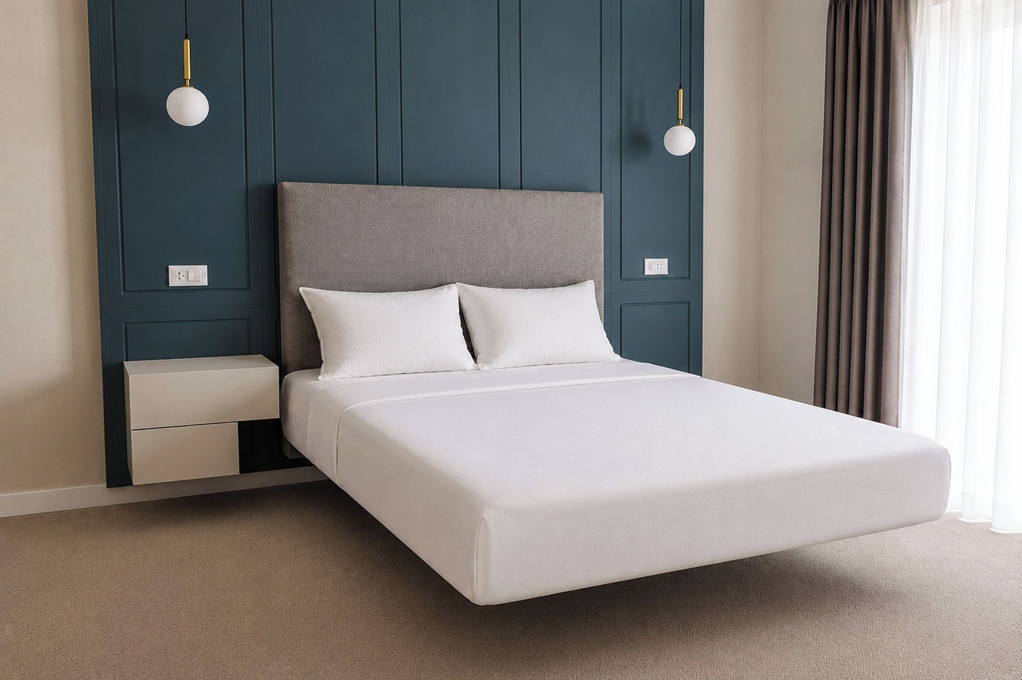 Una cama con cabecera gris, ropa de cama blanca y dos mesitas de noche con lámparas.