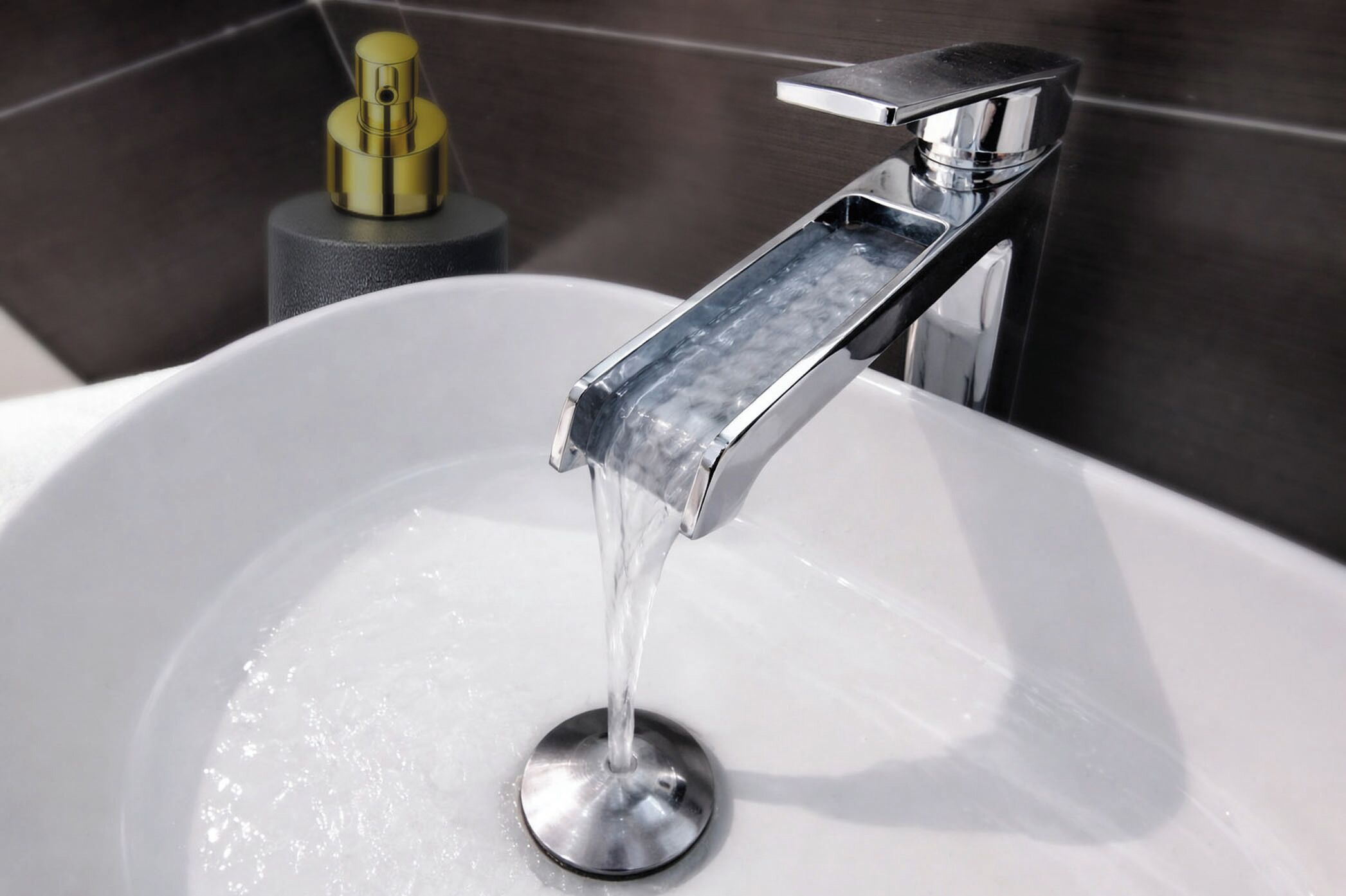 A modern bathroom with a chrome faucet, a white sink, and a yellow soap dispenser.