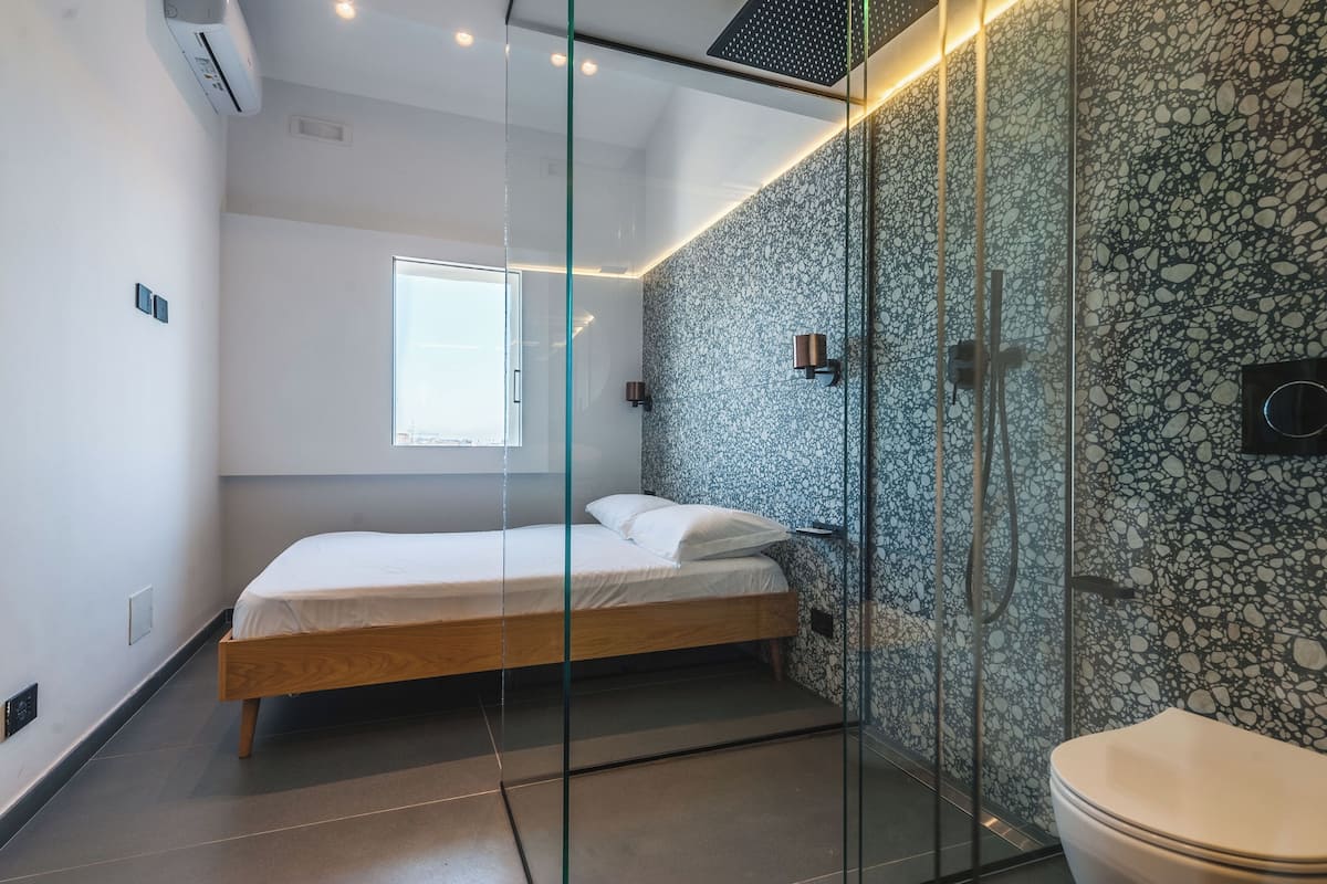 Une chambre moderne avec une douche en verre, un lit et des toilettes.