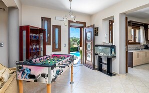 A room with a foosball table, a fish tank, and a kitchen area.