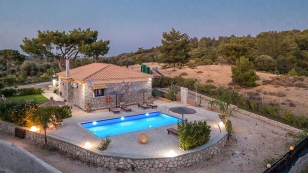 Una villa con piscina, muros de piedra y vistas del paisaje circundante.