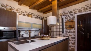 Una cocina moderna con una isla central, horno integrado y un fondo de pared de piedra.