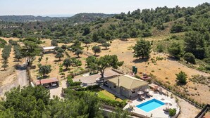 Una villa con piscina, mobiliario de exterior y vistas a las colinas circundantes.