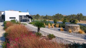Una casa moderna con un patio, mobiliario exterior y un muro de piedra.