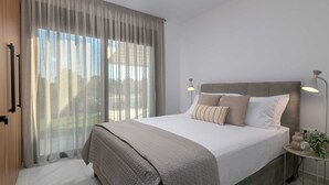 Un dormitorio con cama, cortinas, lámpara de noche y mesita de noche con una planta.