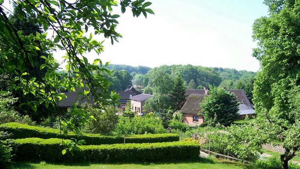 A rural village with traditional houses, lush greenery, and a well-maintained garden. - Pension Malu wo der Tag ab 6 Uhr mit einem guten Frühstück beginnt (Todenbüttel)