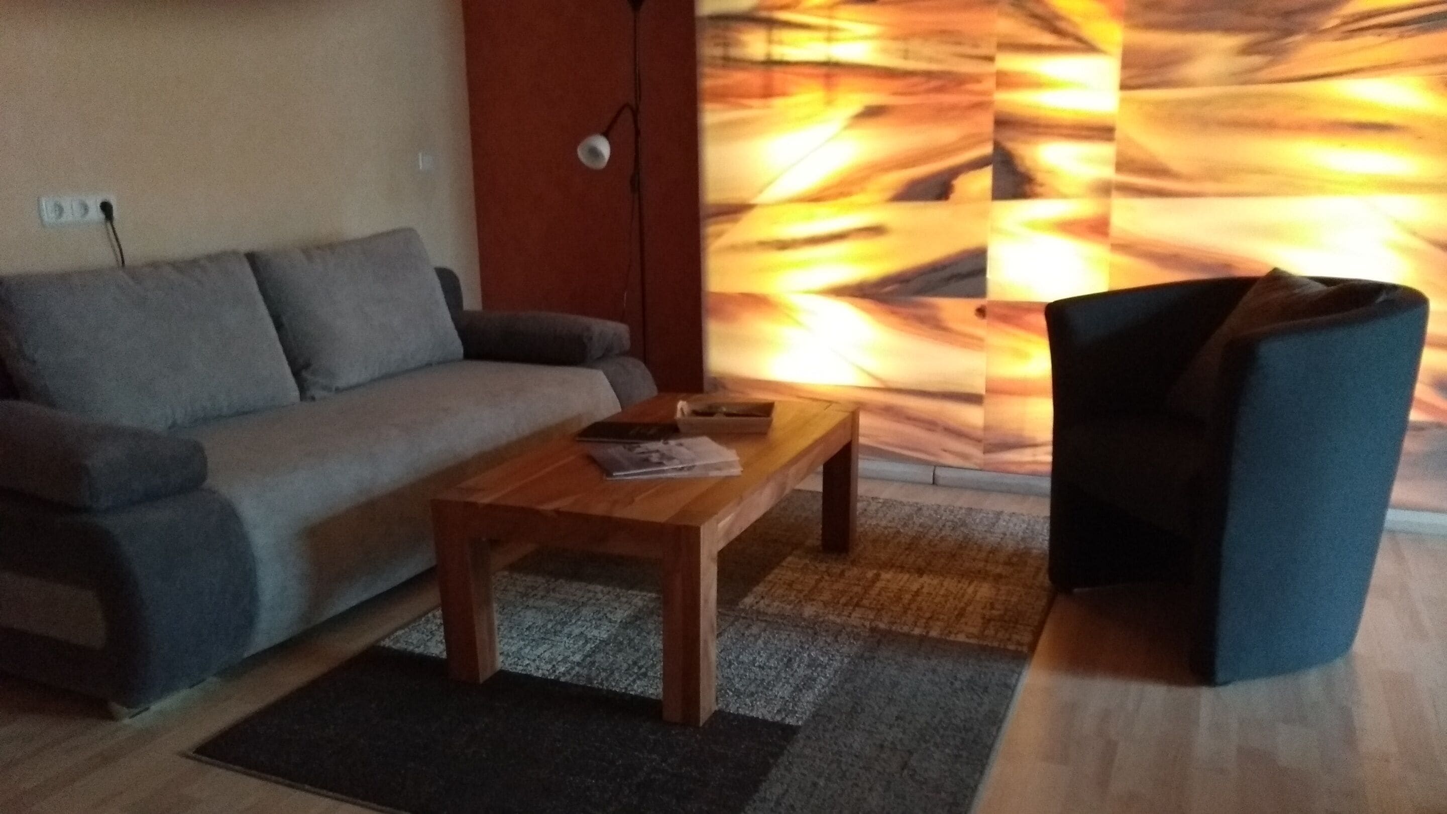 Ein Wohnzimmer mit einer Couch, einem Holztisch und einem dunklen Sessel.