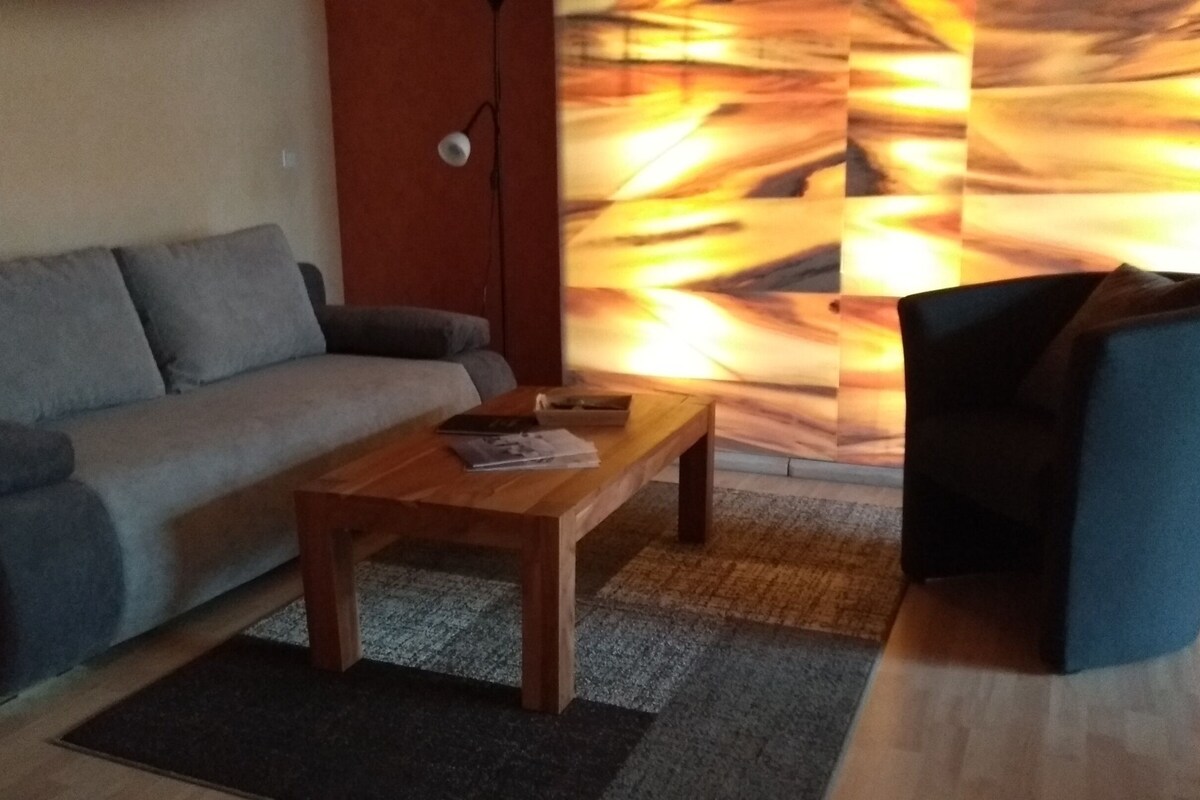 A living room with a sofa, a wooden coffee table, and a dark armchair.