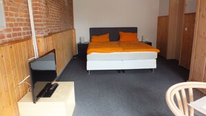 A bedroom with a bed, a TV, and a chair. - Pension Malu wo der Tag ab 6 Uhr mit einem guten Frühstück beginnt (Todenbüttel)